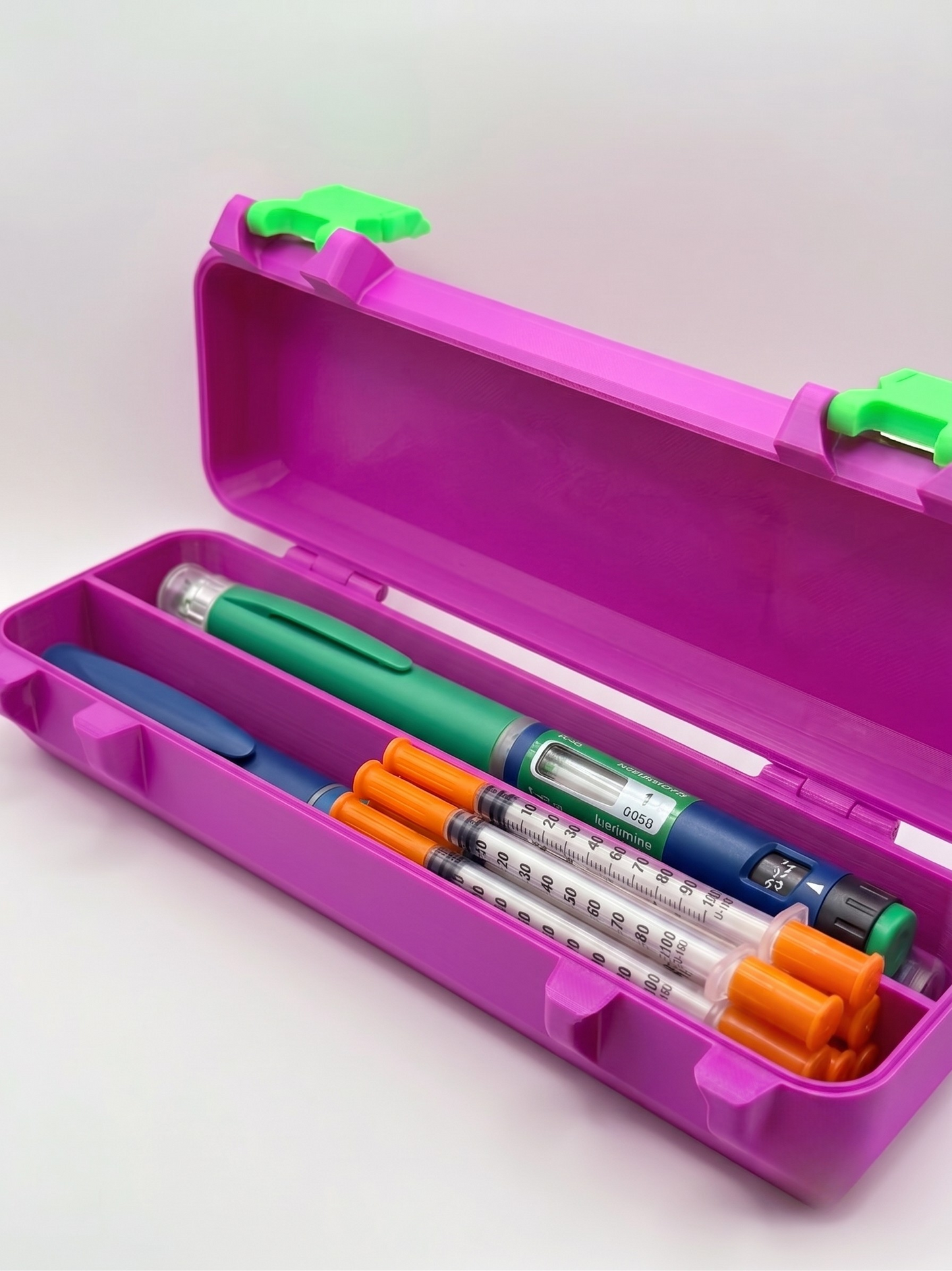 Purple and green 3D printed syringe storage case loaded with syringes and pens — The Protector by Vial Buddy